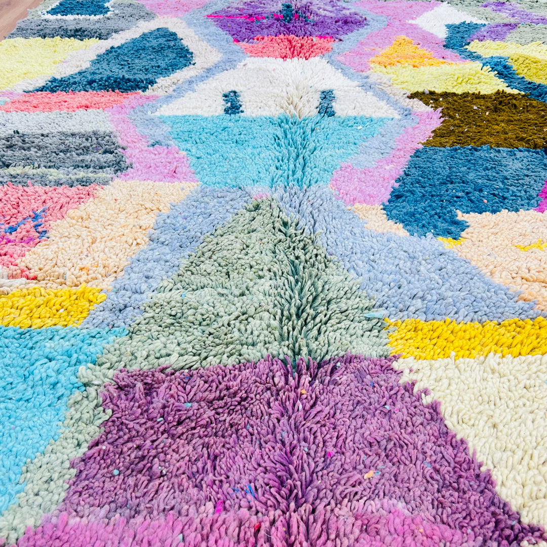 Colorful geometric Moroccan rug with turquoise, pink, yellow, and lavender patterns. Handwoven vintage Berber wool design.