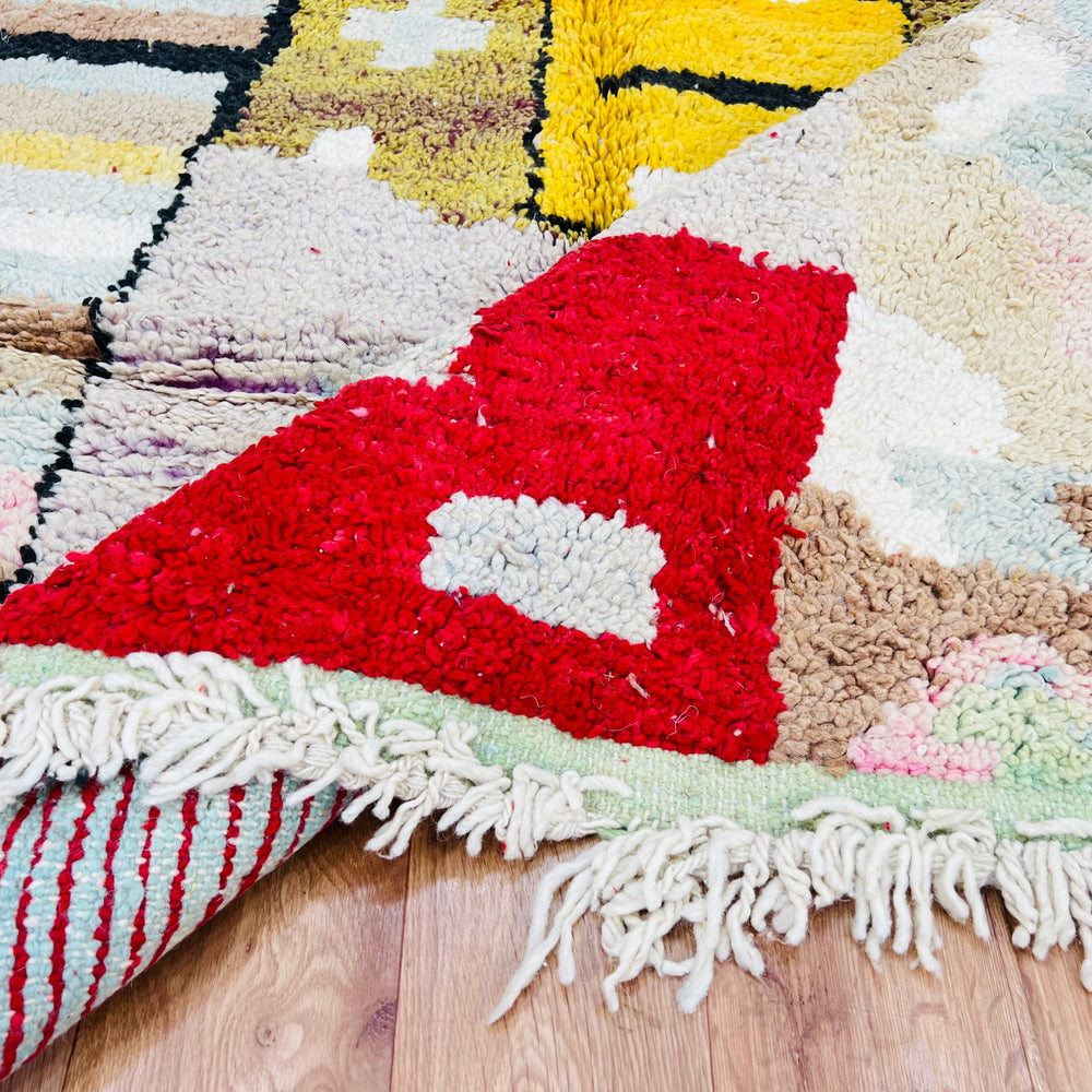 Vintage Moroccan Berber rug with geometric patterns in red, mustard, pastel pink, and sky blue, showcasing tribal designs.