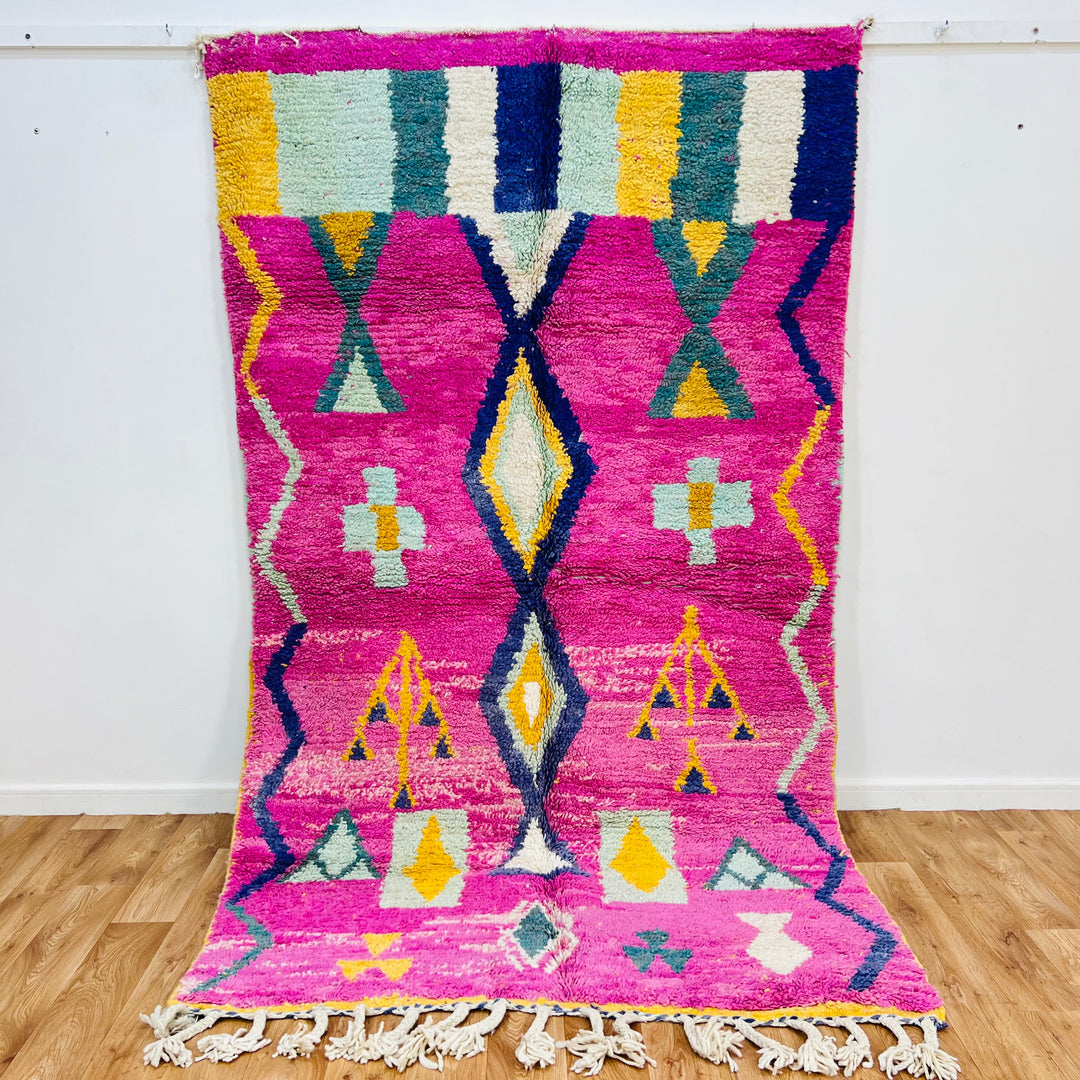 Pink Moroccan rug with tribal symbols, handwoven by Berber artisans, featuring vibrant diamond and tree motifs. Size: 164x155 cm.