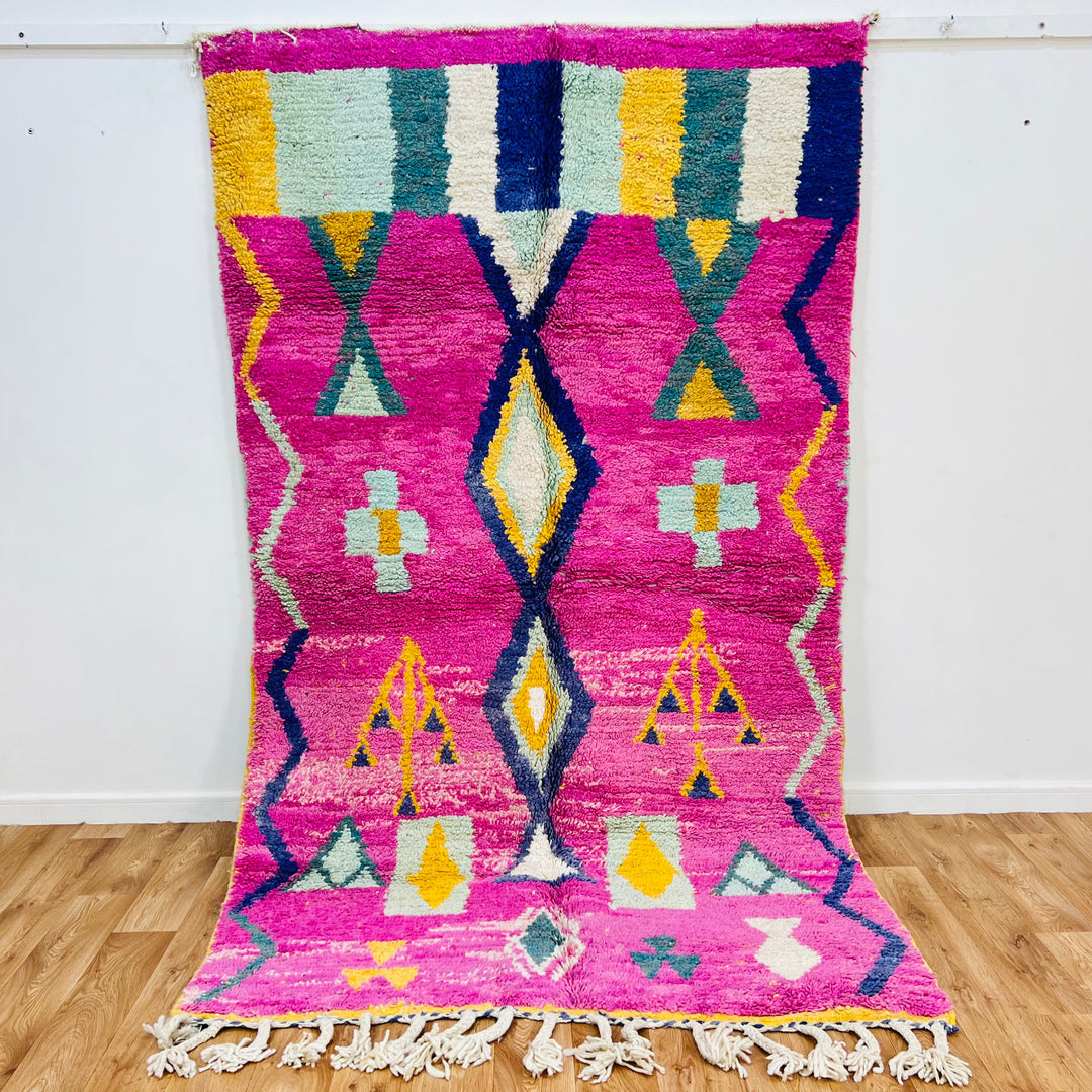 Pink Moroccan Berber rug with tribal motifs in mustard, teal, navy on a pink background, 164x155 cm, traditional wool decor.