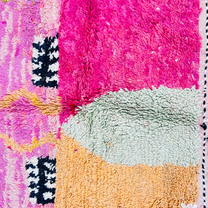Pink abstract Moroccan rug with vivid colors and intricate design, showcasing black-and-white, mint green, and yellow accents.
