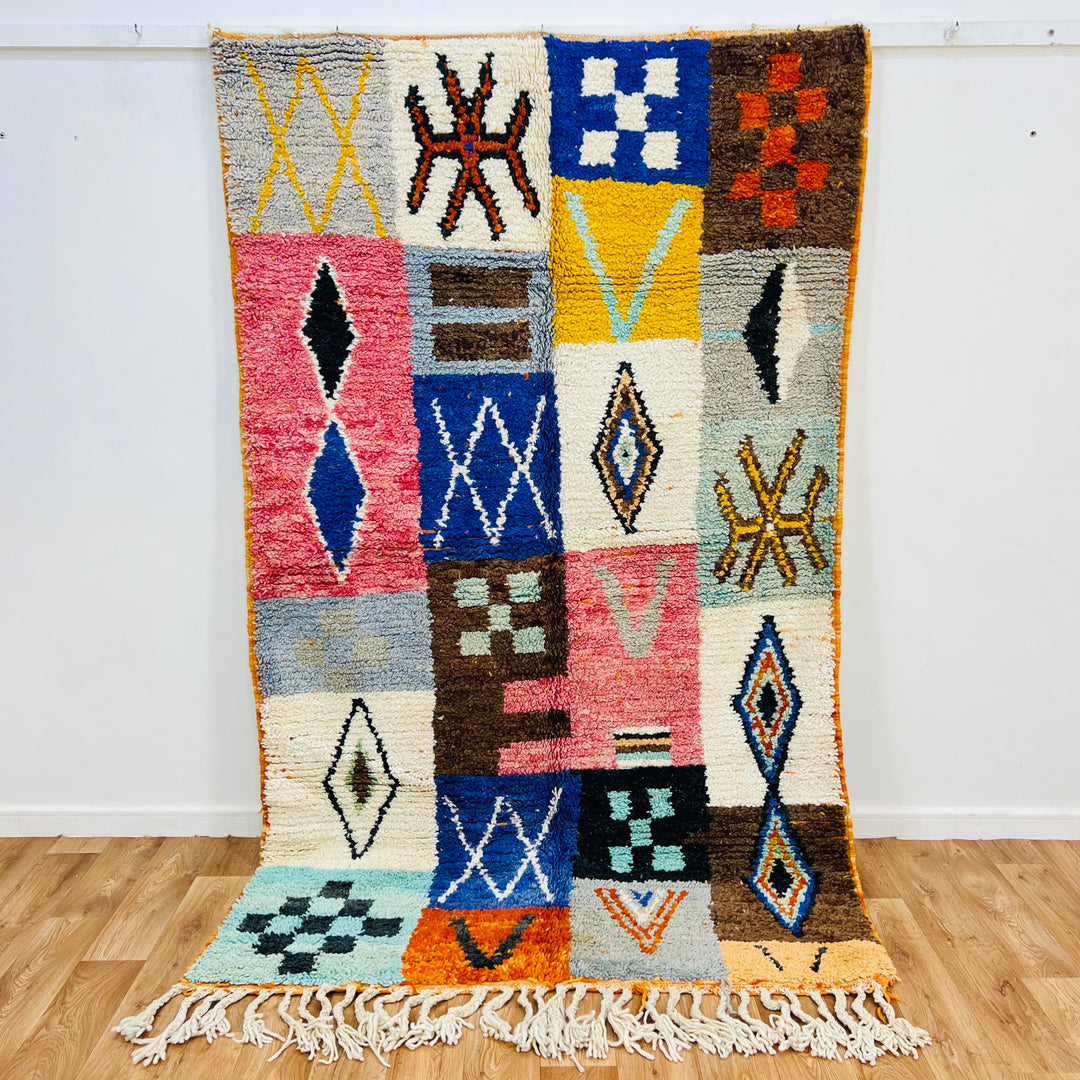 Colorful Moroccan patchwork wool rug with tribal symbols, 249x149cm, featuring red, blue, amber, and ivory tones.