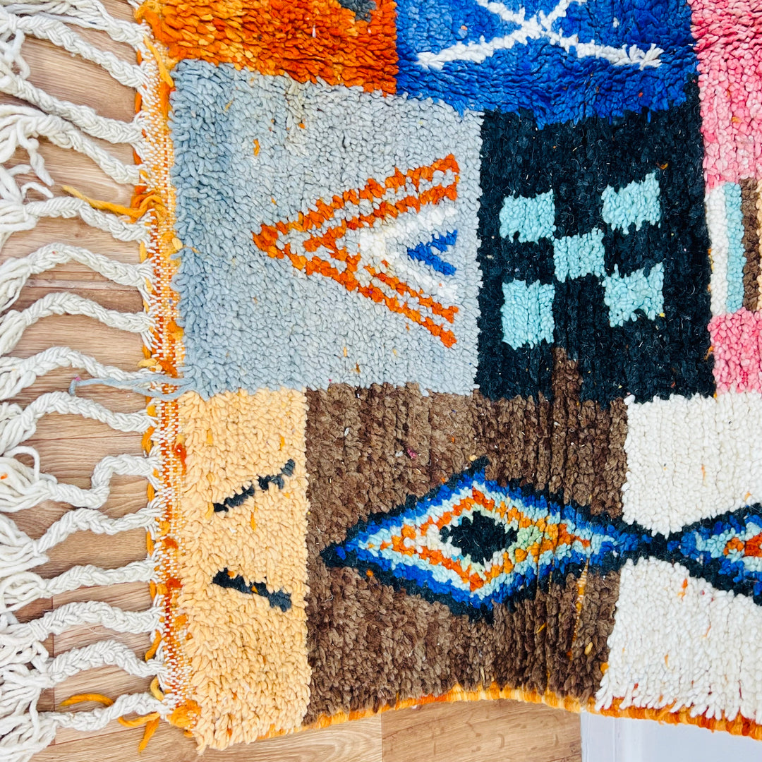 Colorful Moroccan patchwork wool rug with tribal symbols, 249 x 149 cm, featuring red, blue, amber, and ivory tones.