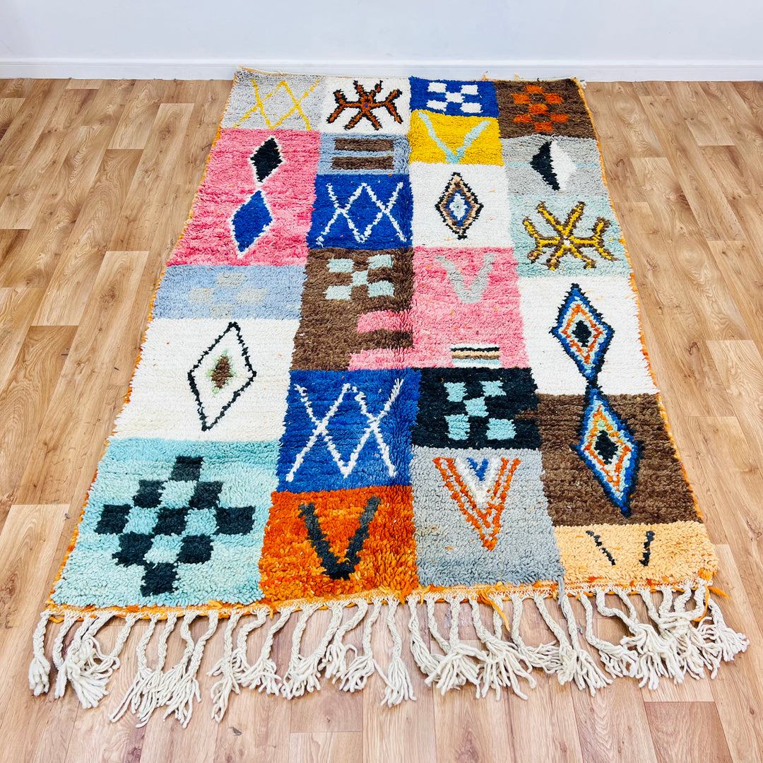 Colorful Moroccan Berber wool rug with tribal symbols in red, blue, amber. Handmade patchwork design, perfect as a traditional carpet.