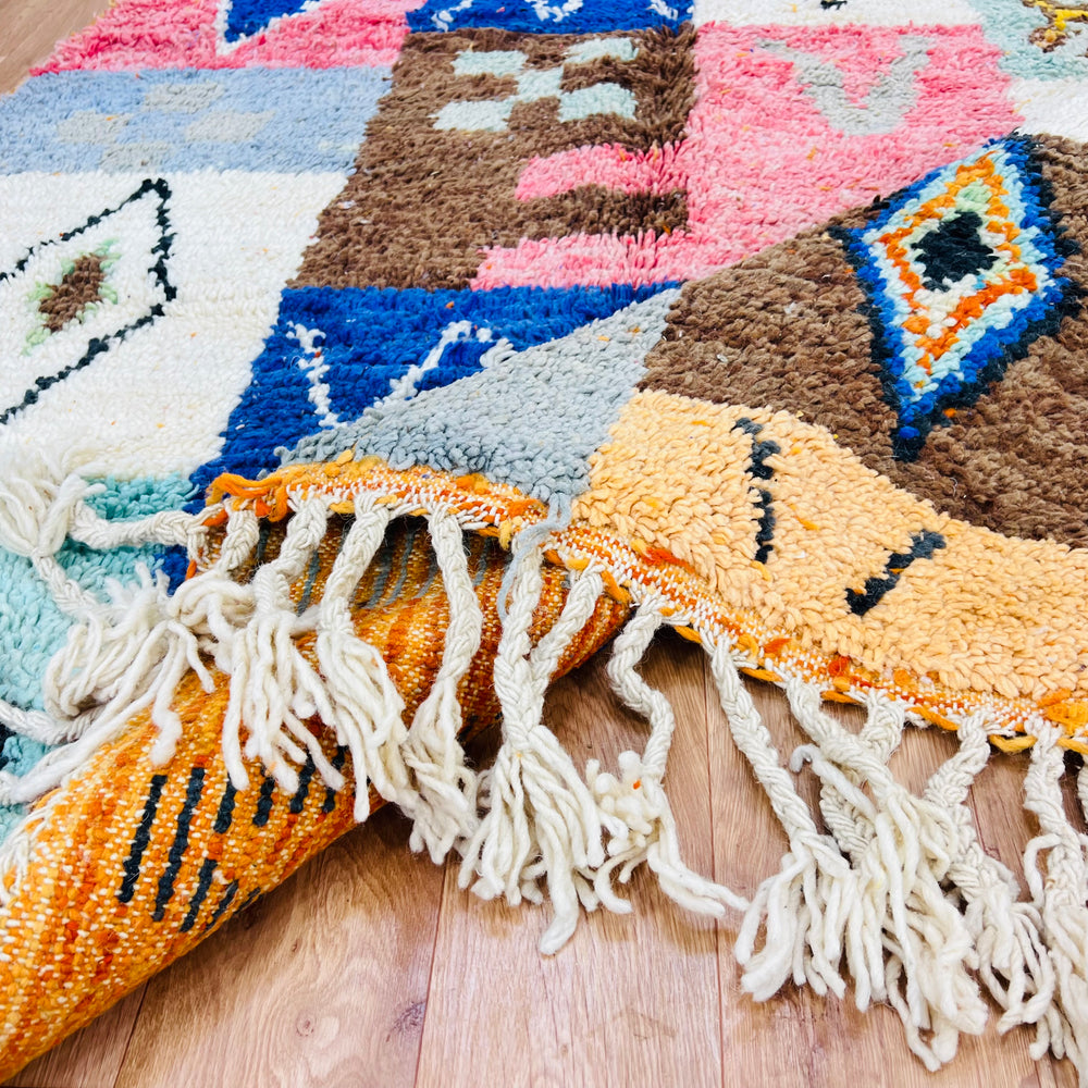 Colorful Moroccan patchwork wool rug with tribal motifs and vibrant hues, handmade with traditional Berber techniques.