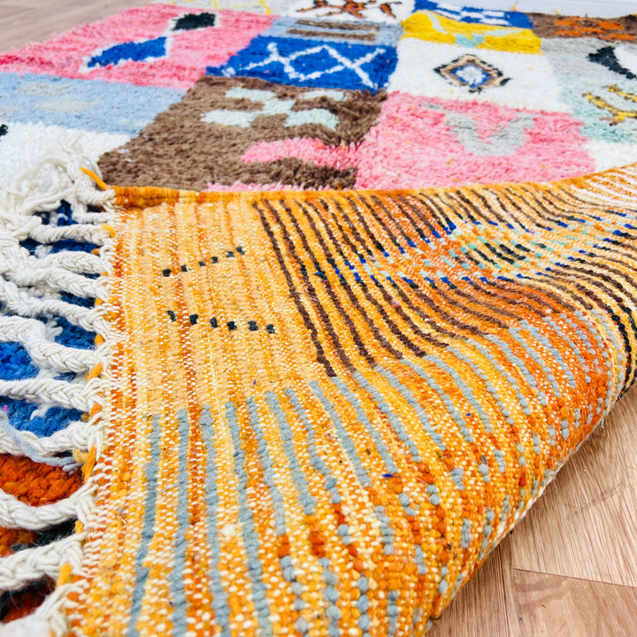 Colorful Moroccan patchwork wool rug showcasing vibrant Berber designs with reds, blues, and amber tones, 249 x 149 cm.
