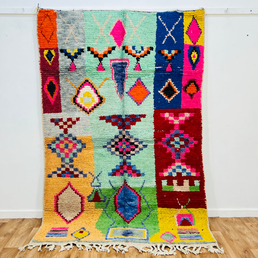 Colorful vintage Moroccan rug with geometric patterns in pink, turquoise, orange, red, and blue. Handcrafted Berber style.