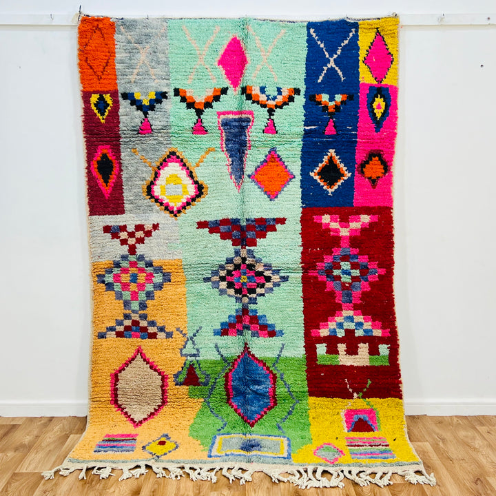 Colorful vintage Moroccan rug with geometric patterns in pink, turquoise, orange, red, and blue, handcrafted by Berber artisans.