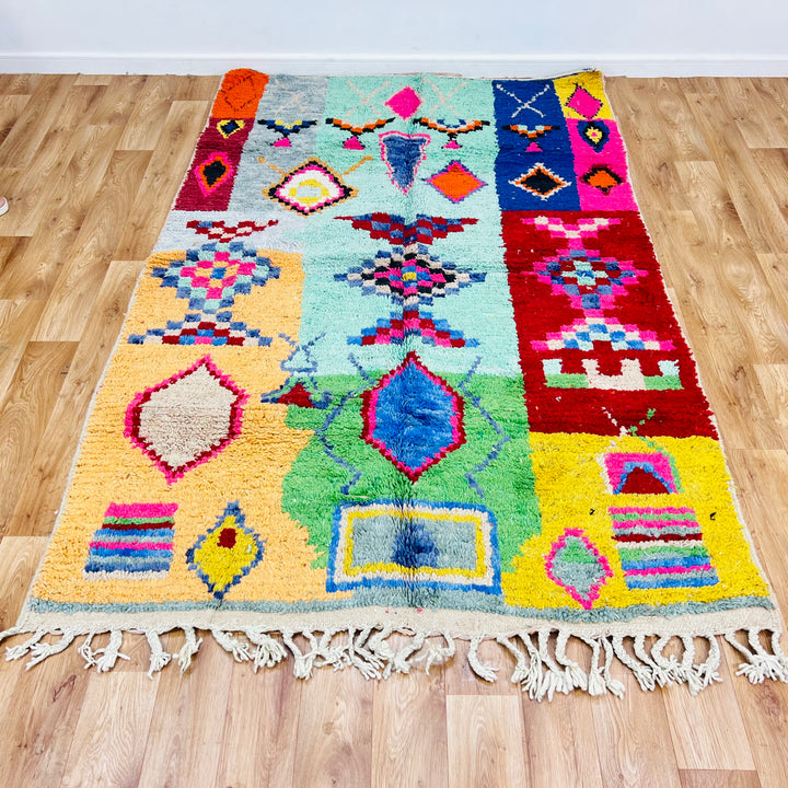 Colorful vintage Moroccan rug with geometric patterns, featuring vibrant shades of pink, turquoise, orange, and blue.