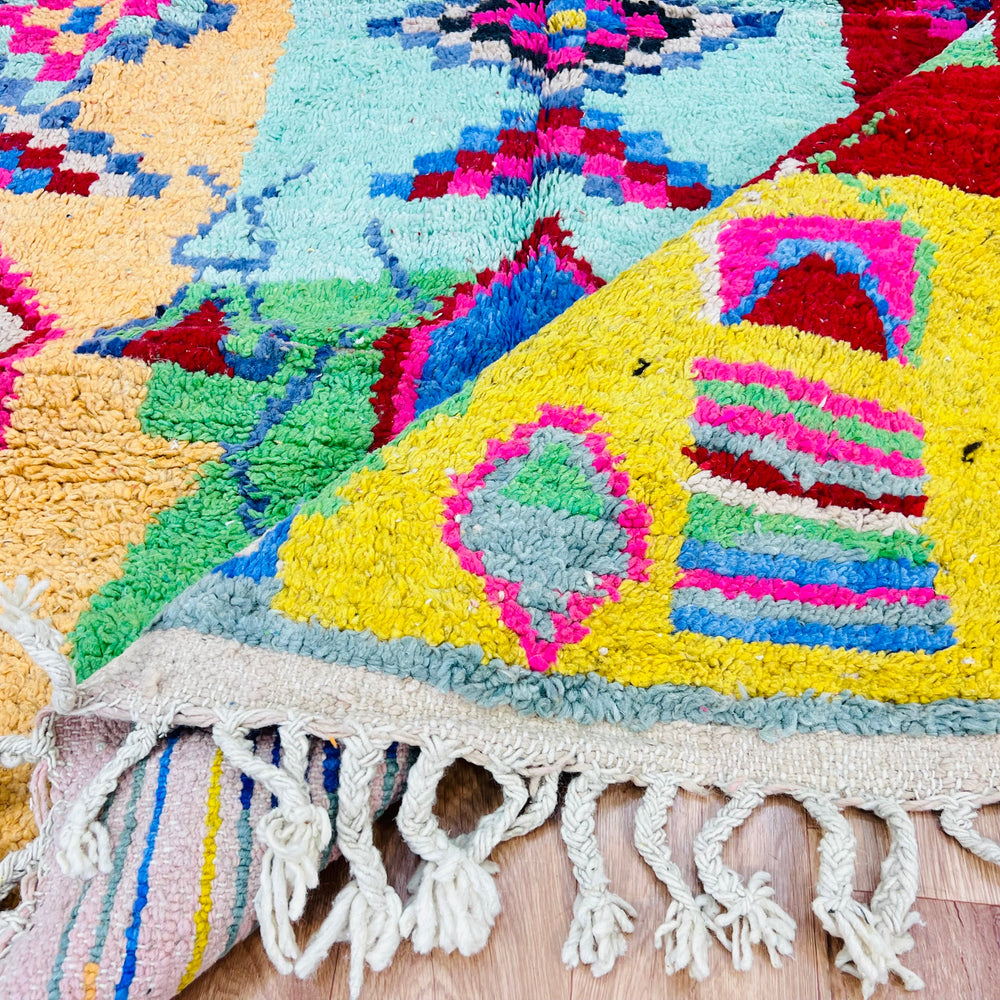 Colorful vintage Moroccan Berber rug with bold geometric patterns in pink, turquoise, orange, and blue, handcrafted from 100% wool.