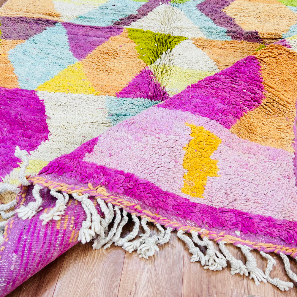 Colorful geometric Moroccan wool rug 419, featuring vibrant patchwork design with pink base and tassels, handwoven by Berber artisans.