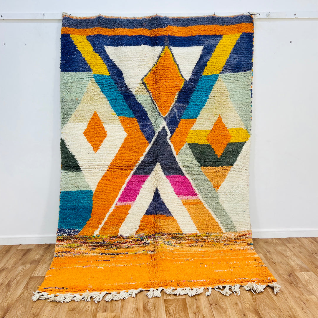 Colorful Moroccan wool rug with geometric diamond and X-shape motifs in orange, navy, fuchsia, ivory, and teal, 255x171 cm.