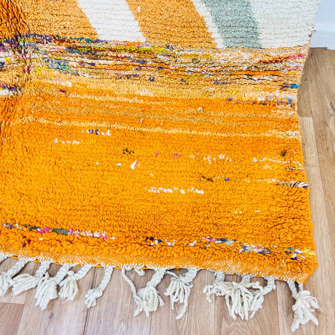 Vibrant Moroccan wool rug with colorful geometric patterns, showcasing handmade Berber artistry and tassel details. Perfect for a cozy space.