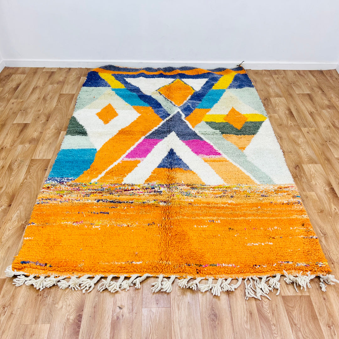 Large colorful Moroccan wool rug with orange, navy, and teal diamond motifs, handwoven by Berber artisans, 255x171 cm.