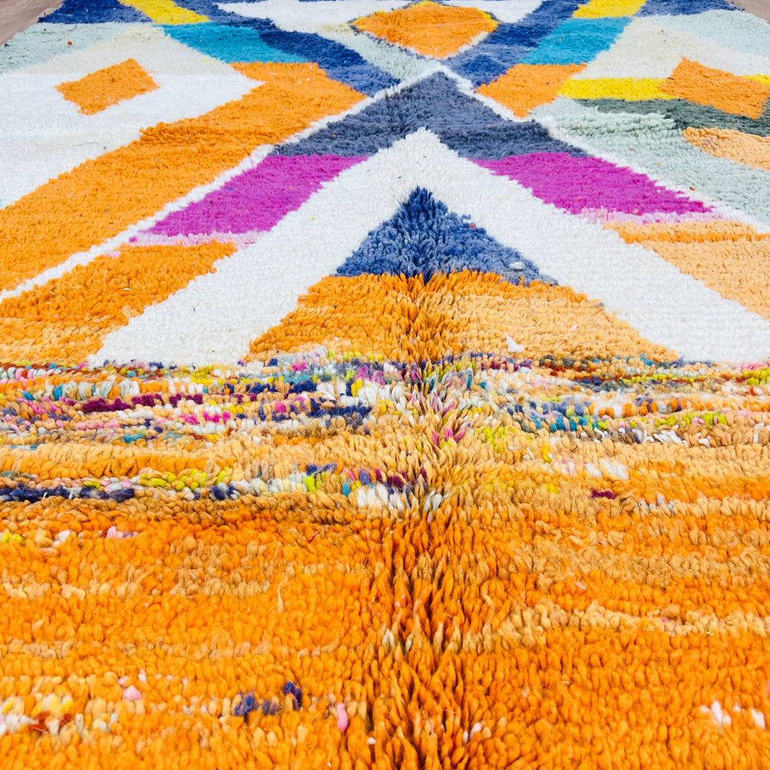 Large Moroccan wool rug with colorful geometric patterns in orange, navy, fuchsia, ivory, and teal, 255x171 cm.