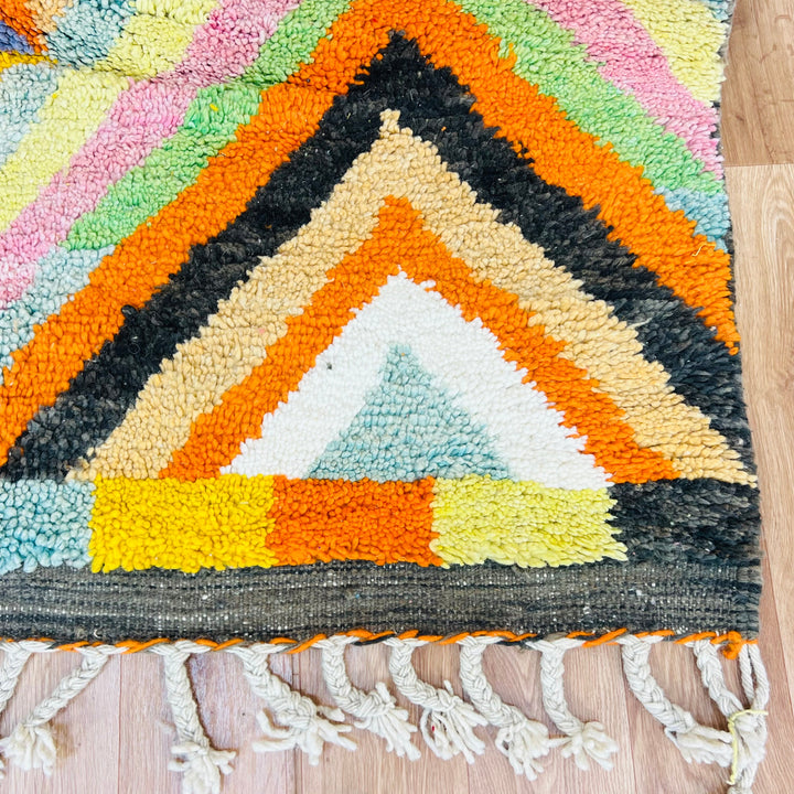 Colorful Moroccan rug with chevron pattern, featuring vibrant orange, pink, green, and yellow tones. Traditional Berber design.