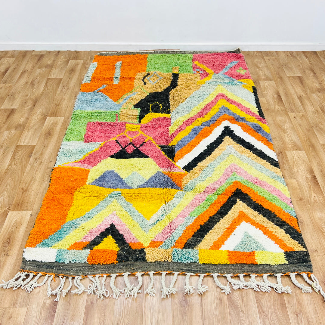 Colorful Chevron Moroccan Rug with zigzag pattern, handwoven by Berber artisans, featuring bold orange, pink, and green hues.
