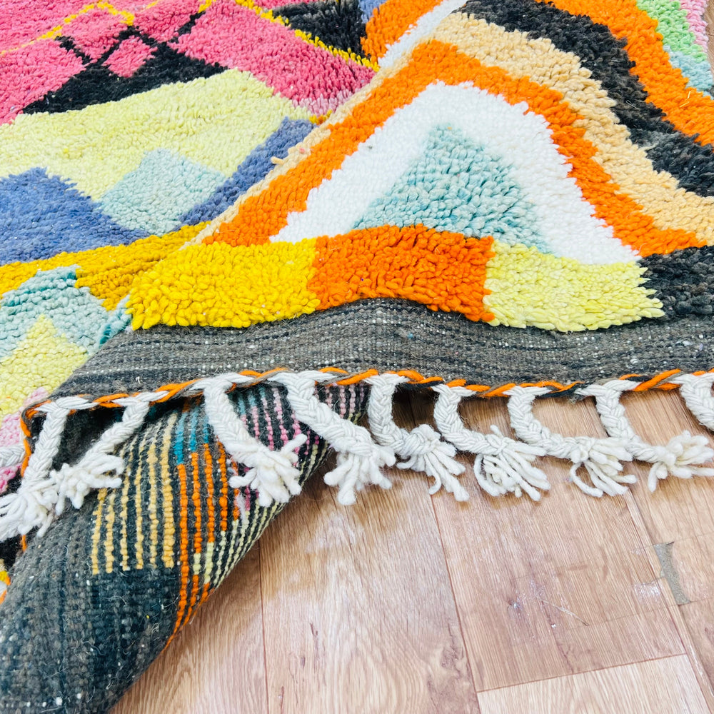 Colorful Chevron Moroccan rug with vibrant zigzag pattern in orange, pink, green, and blue, handwoven by Berber artisans.