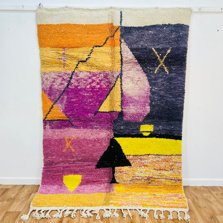 Vintage Moroccan sunset rug with vibrant purple, yellow, and orange patterns, featuring desert motifs and Berber design.