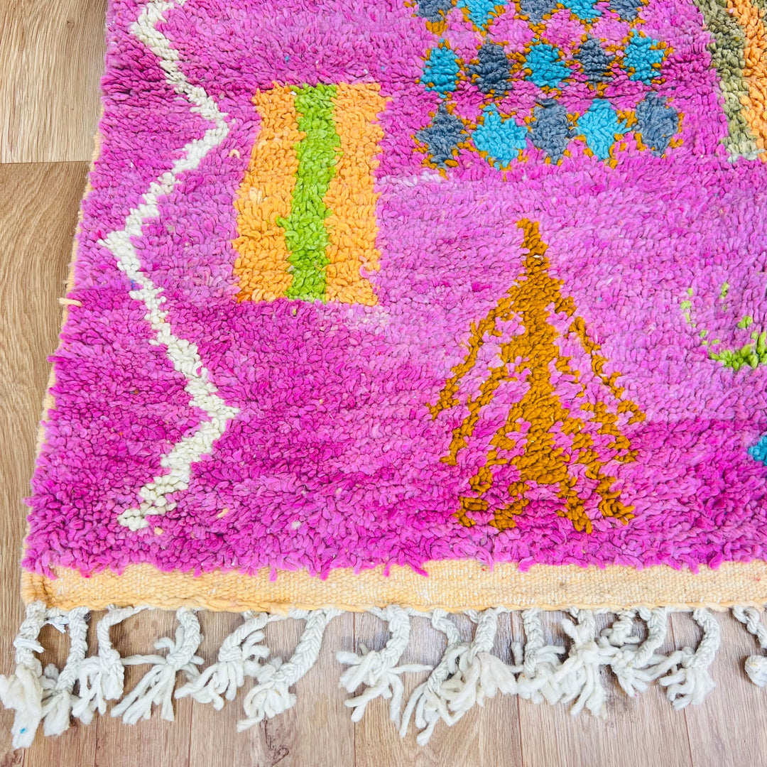 Colorful Berber Moroccan rug with tribal patterns on pink and orange base, handmade wool by Berber artisans, 9x5 ft.