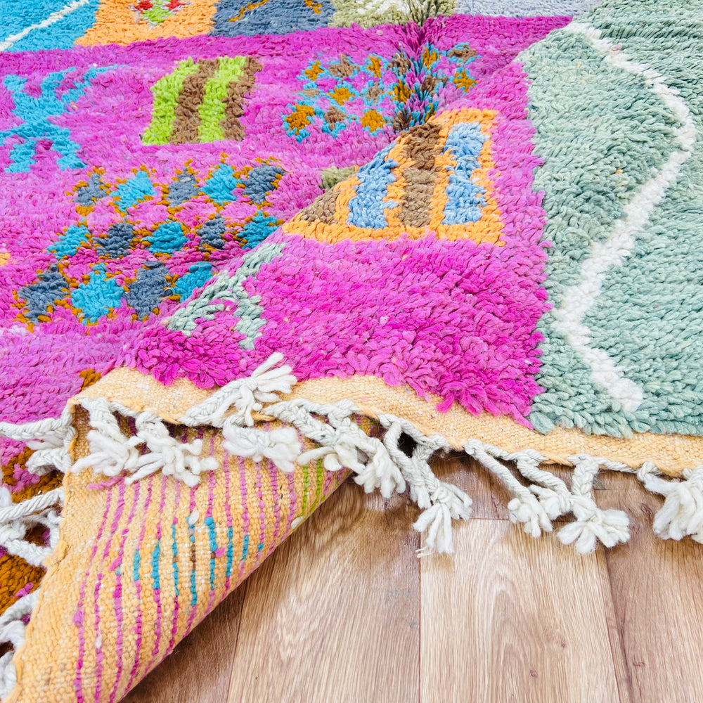 Colorful handmade Berber Moroccan rug with tribal patterns in pink, orange, and green. Woven wool, 9x5 ft. Traditional Moroccan style.