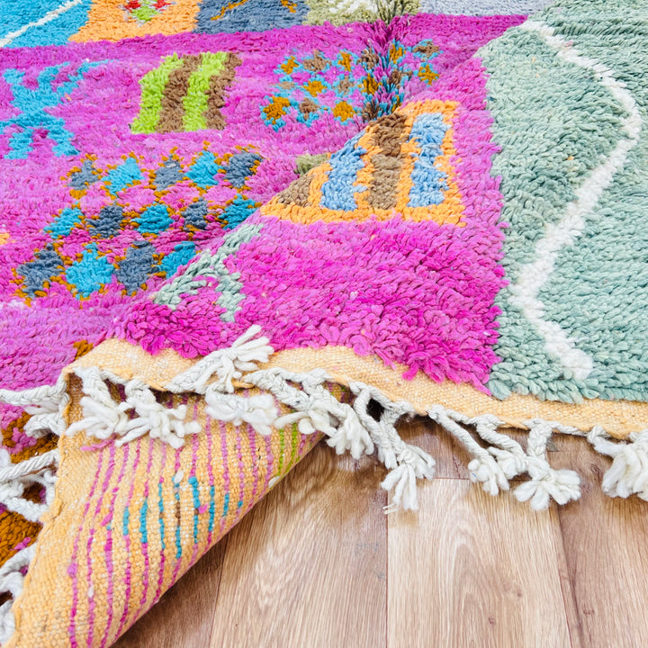Colorful handmade Berber Moroccan rug with tribal patterns in pink, orange, and green. Woven wool, 9x5 ft. Traditional Moroccan style.