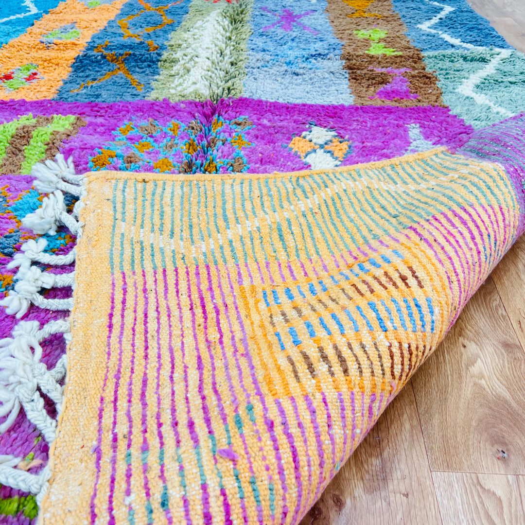 Colorful Berber Moroccan rug with tribal symbols on a pink and orange base, 9x5 ft. Handmade with premium wool, ideal for home decor.