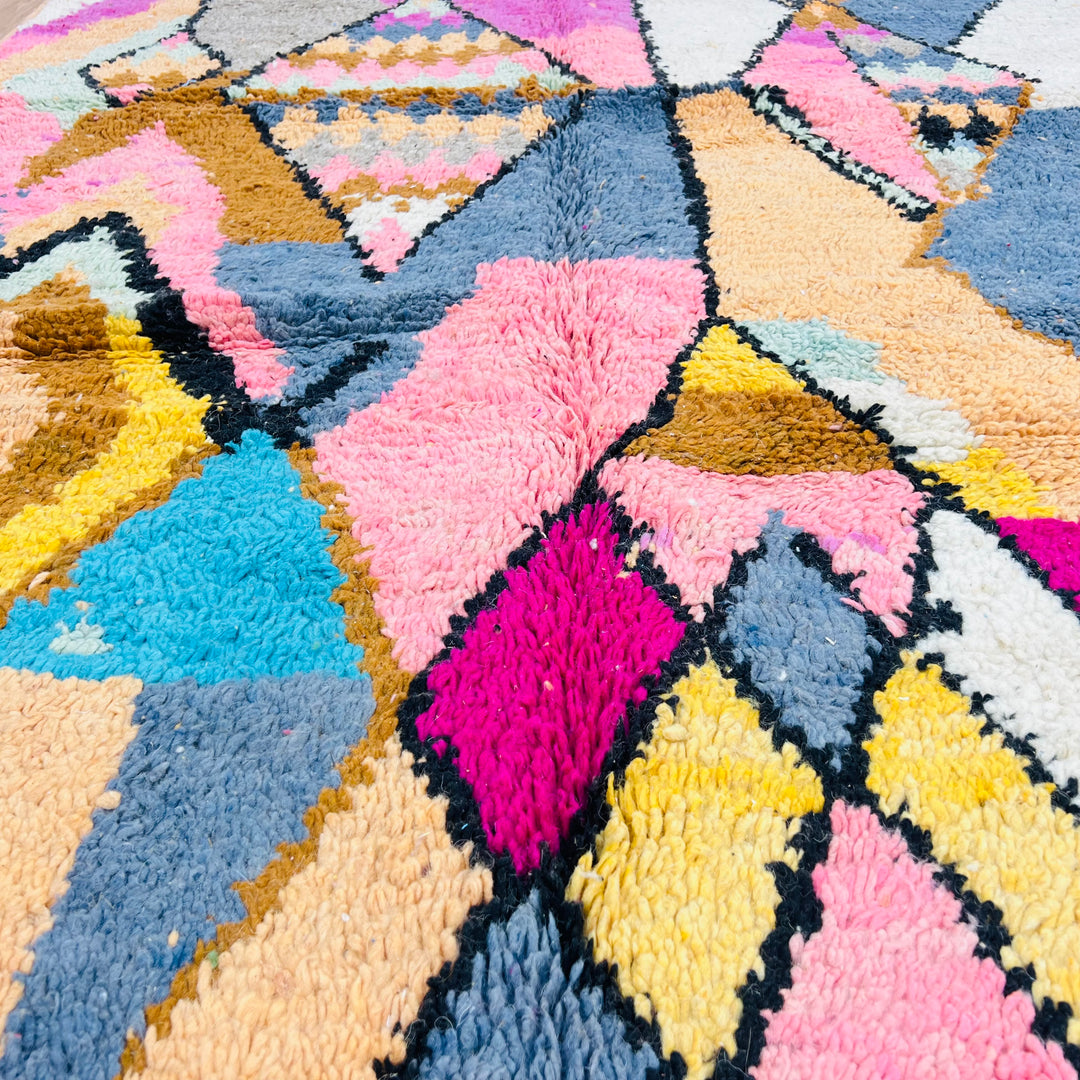 Colorful vintage Moroccan wool rug with geometric diamond pattern in pink, blue, and yellow, perfect for boho interiors, size 256x169 cm.