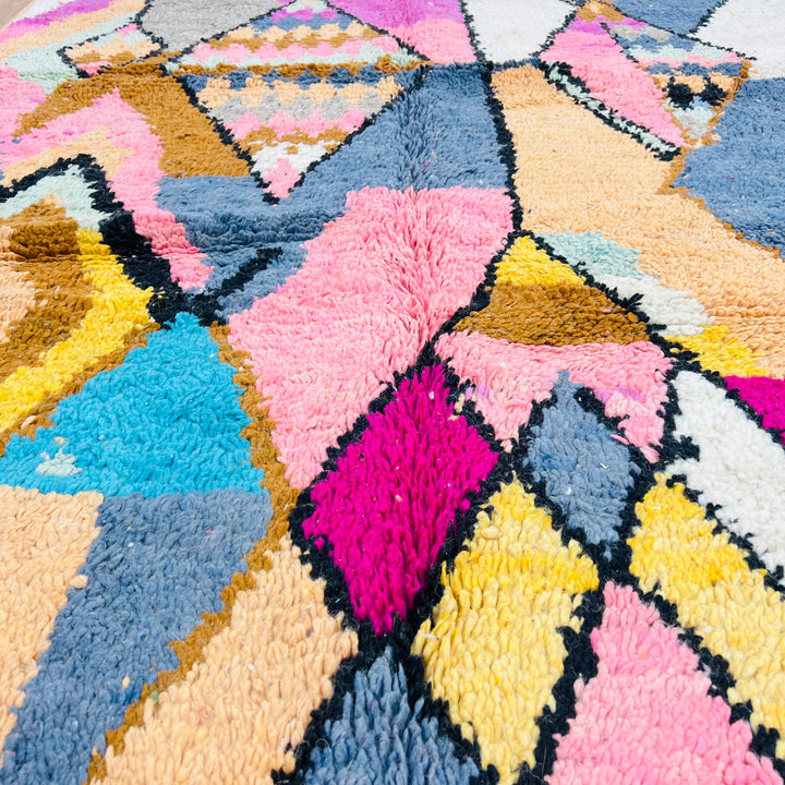 Colorful vintage Moroccan wool rug with geometric diamond pattern in pink, blue, and yellow, perfect for boho interiors, size 256x169 cm.