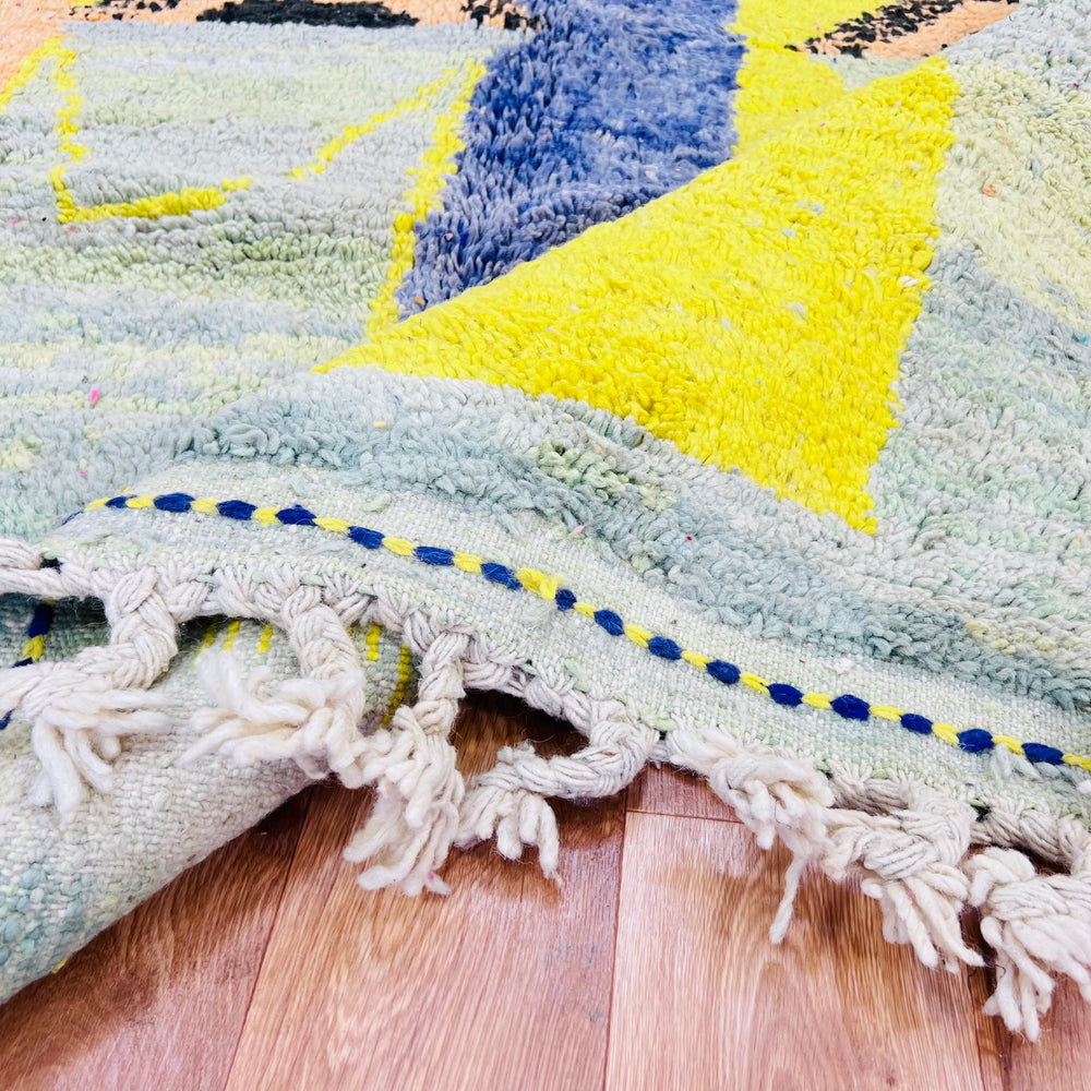 Yellow tribal abstract Moroccan wool rug showcasing geometric patterns and fringe, featuring mustard yellow, blue, and green hues.
