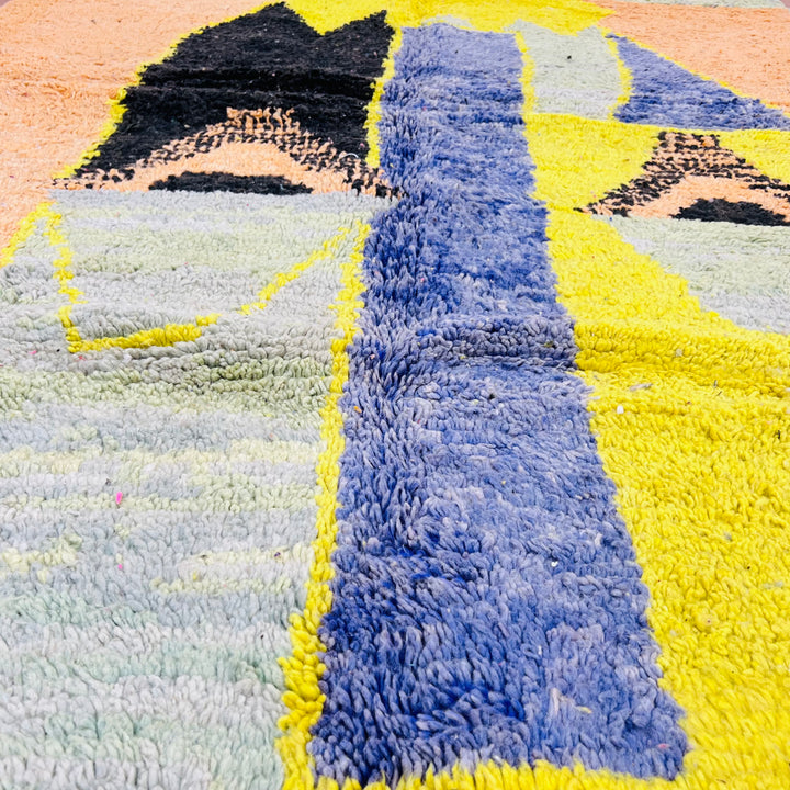 Yellow Moroccan wool rug with abstract tribal designs in mustard, blue, and black hues, dimensions 275x168 cm.