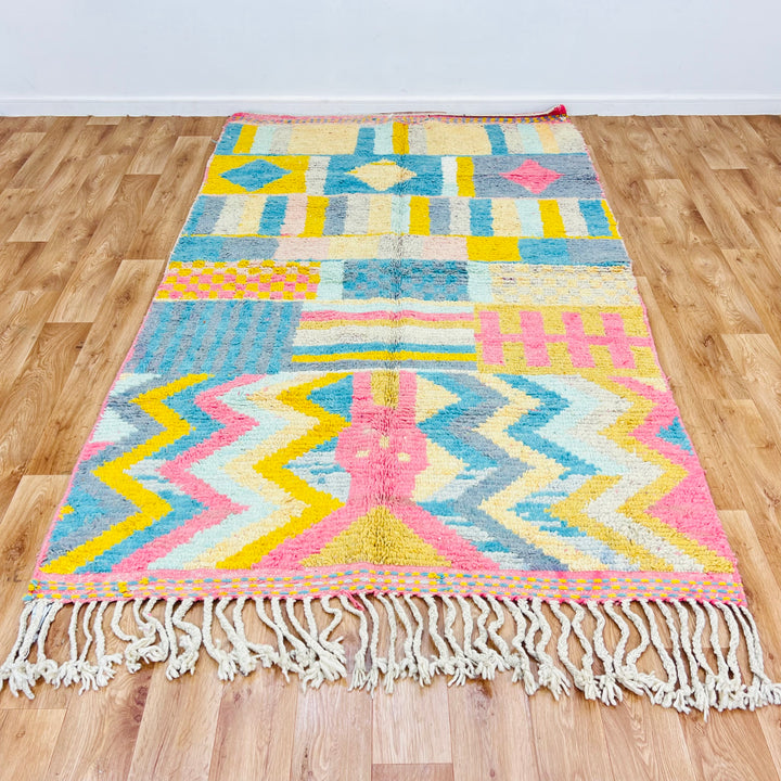 Vintage Moroccan Berber wool rug with colorful geometric patterns in pink, yellow, teal, and grey. Handwoven, 256 x 150 cm.