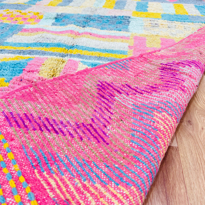 Vintage Moroccan wool rug with colorful Berber patterns in yellow, pink, teal, and grey, handwoven in the Atlas Mountains.