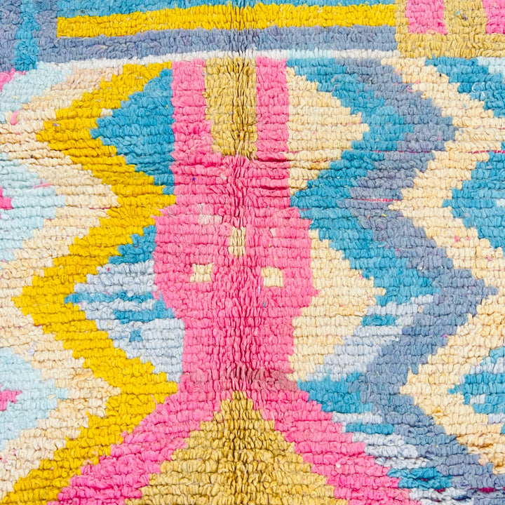 Colorful vintage Moroccan Berber rug with geometric patterns in pink, yellow, teal, and grey, handwoven from wool.