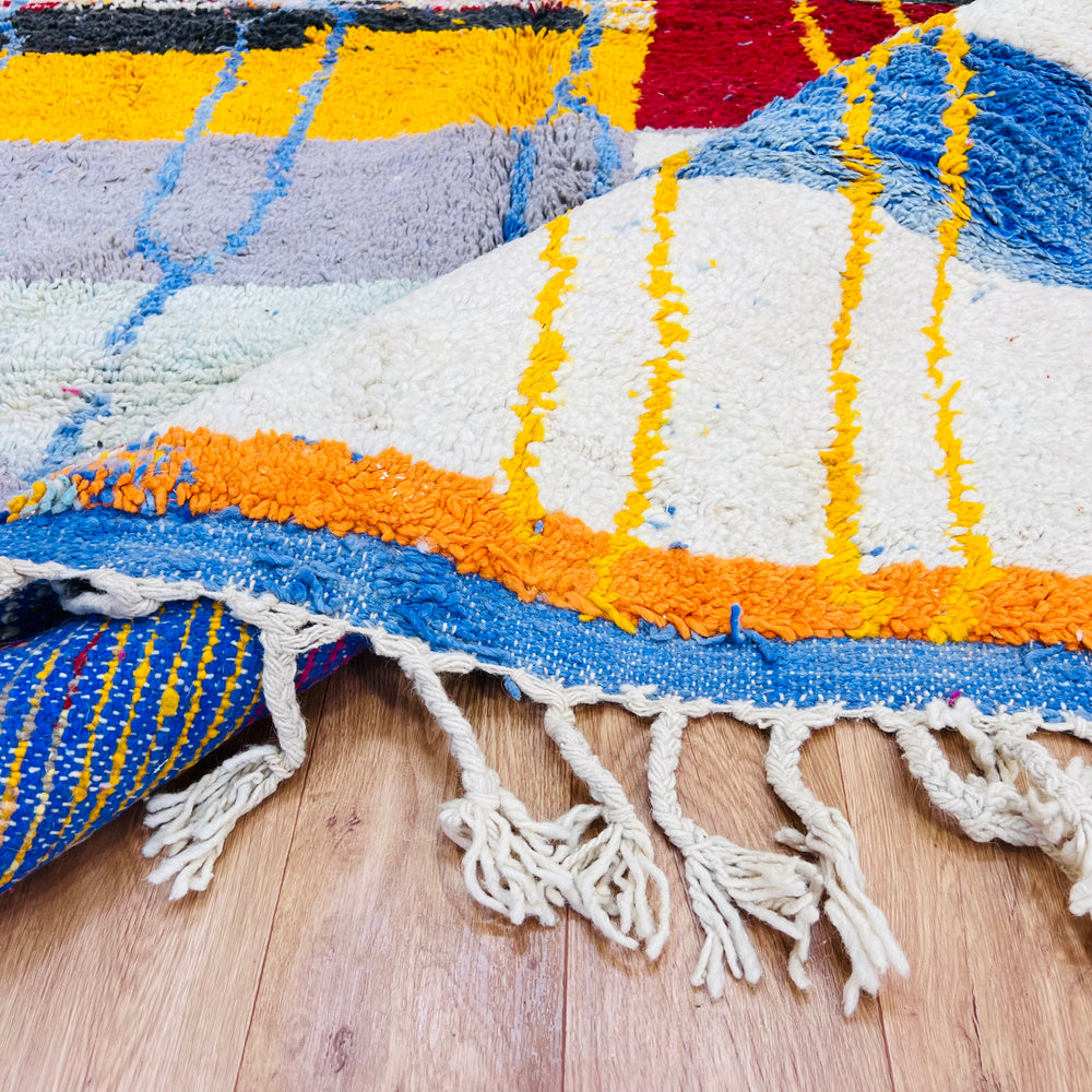 Vintage Moroccan Berber rug with vibrant color blocks, traditional diamond motifs, and tassels, handwoven from soft wool.