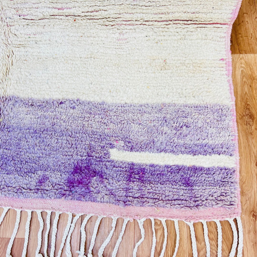 Vintage Moroccan rug with ivory and purple geometric design, hand-knotted wool, fringe detail, perfect for boho and contemporary interiors.