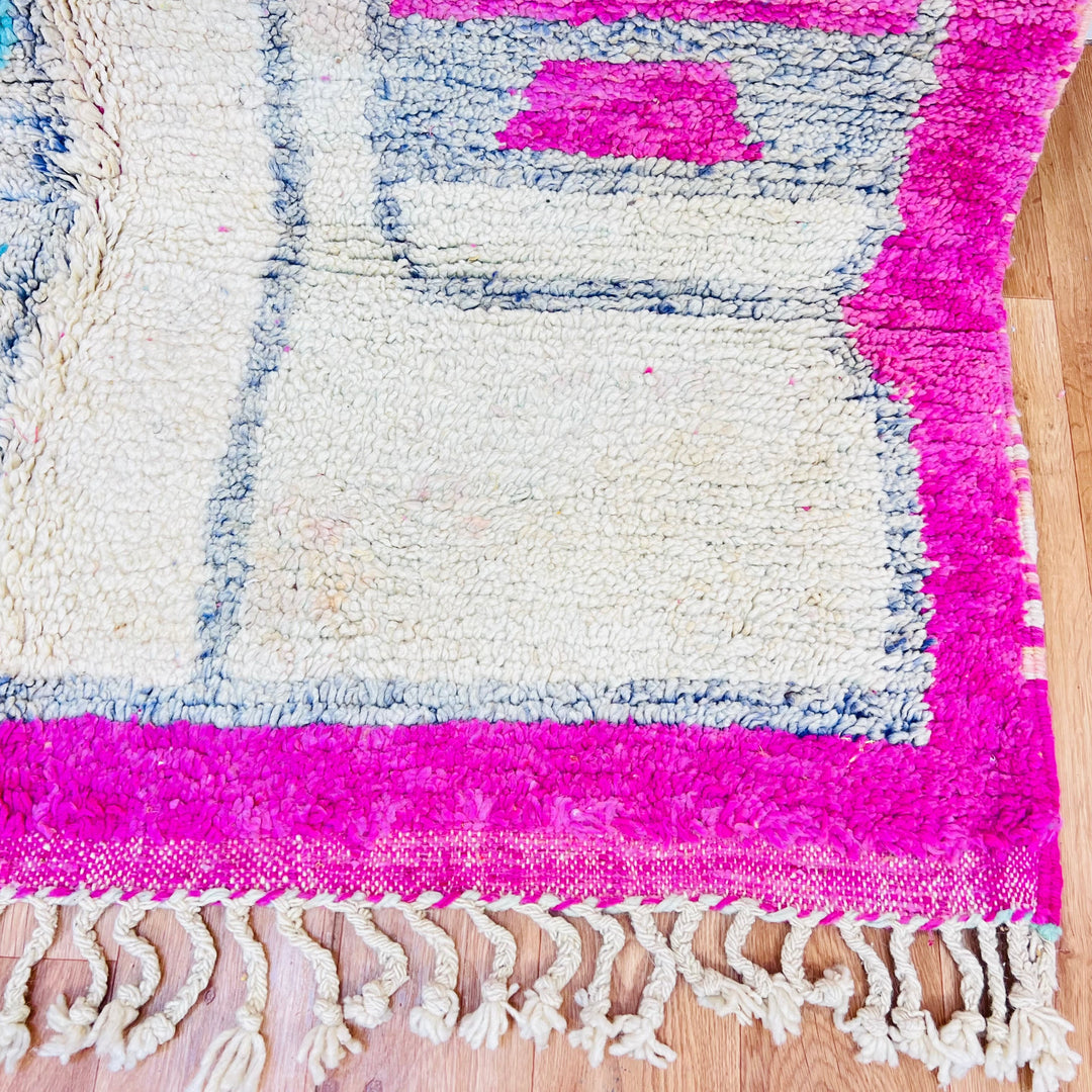 Close-up of a pink vintage Moroccan rug with tribal designs and fringed edges, showcasing traditional Berber craftsmanship.