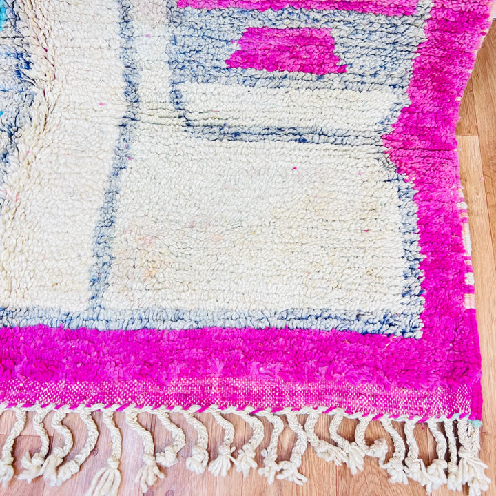 Close-up of a pink vintage Moroccan rug with tribal designs and fringed edges, showcasing traditional Berber craftsmanship.