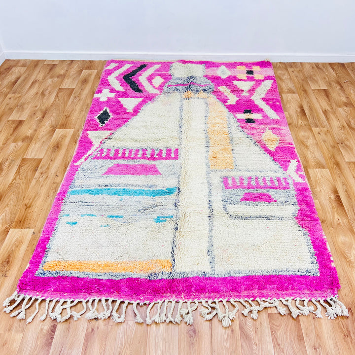 Pink vintage Moroccan rug with tribal motifs, handmade by Berber artisans, featuring cream, orange, and turquoise patterns.