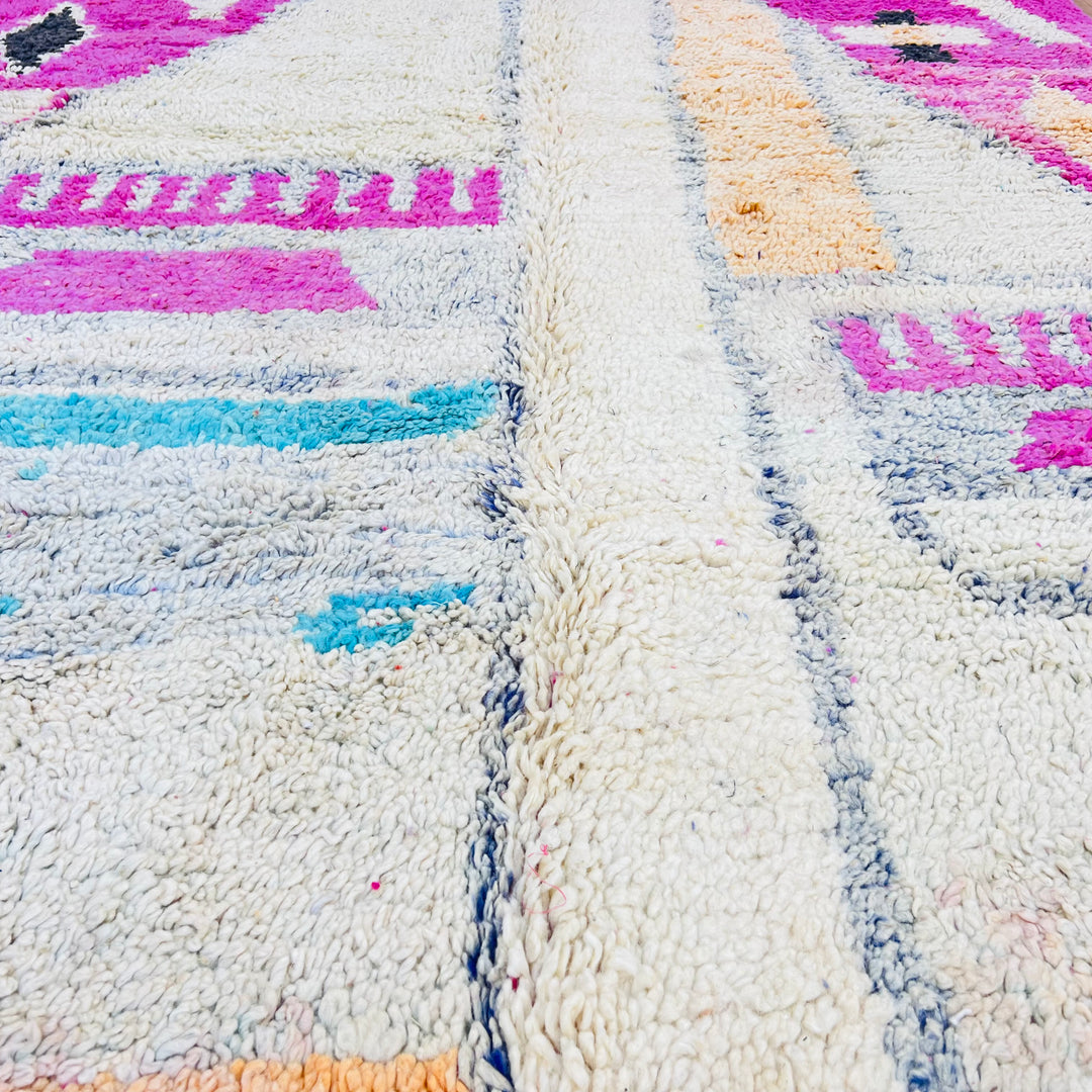 Pink vintage Moroccan rug with tribal patterns in cream, orange, turquoise, and black, handcrafted by Berber artisans.