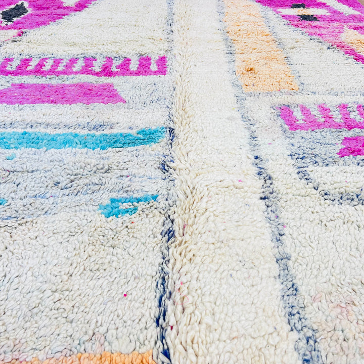Pink vintage Moroccan rug with tribal patterns in cream, orange, turquoise, and black, handcrafted by Berber artisans.