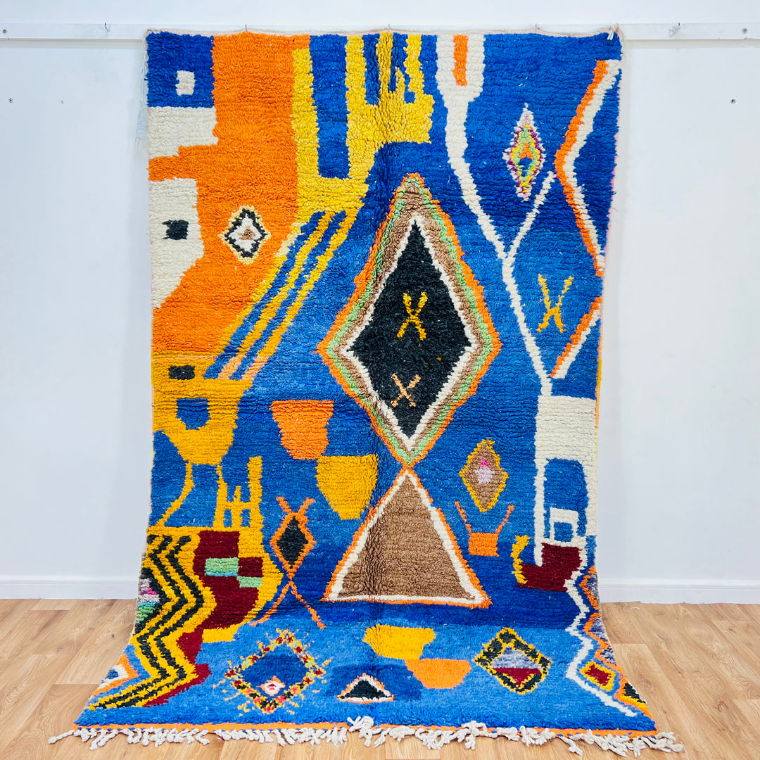 Vintage Moroccan Berber rug with vibrant blue, orange, and tribal designs, featuring diamonds and abstract symbols, 257x160 cm.