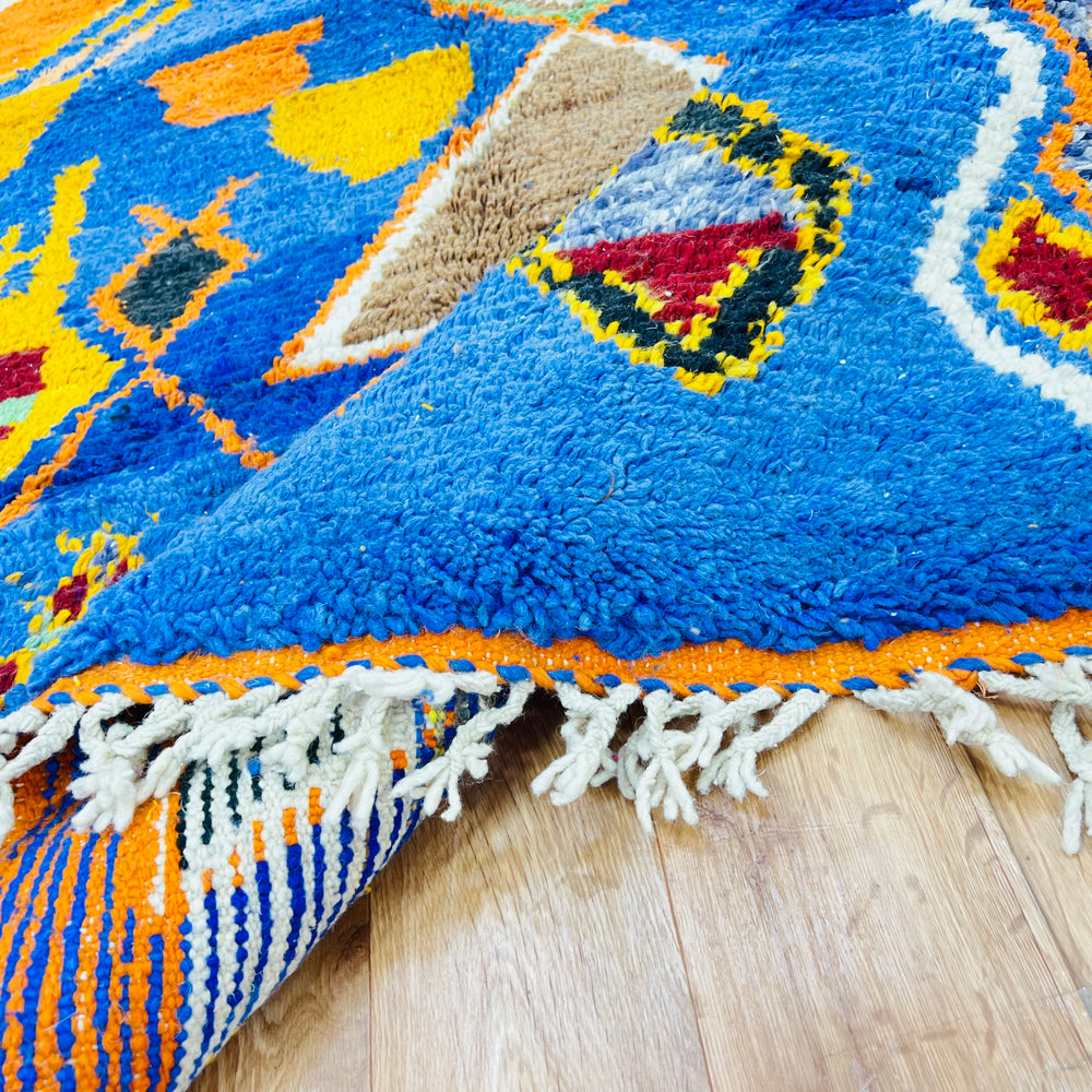 Colorful handmade vintage Moroccan rug with cobalt blue, burnt orange, and tribal symbols, showcasing Berber tribal charm.
