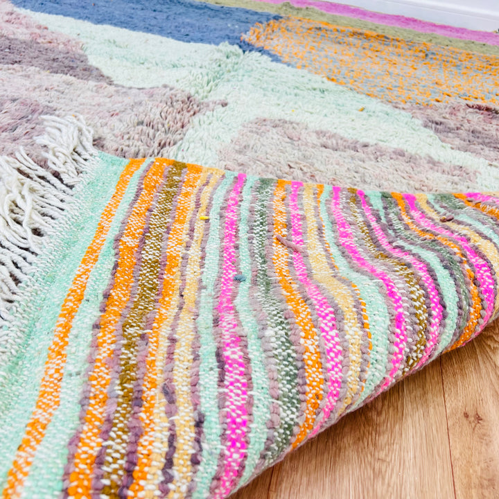 Abstract Moroccan wool rug with colorful stripes, showcasing bohemian design and vibrant desert-inspired colors. Perfect as a statement piece.