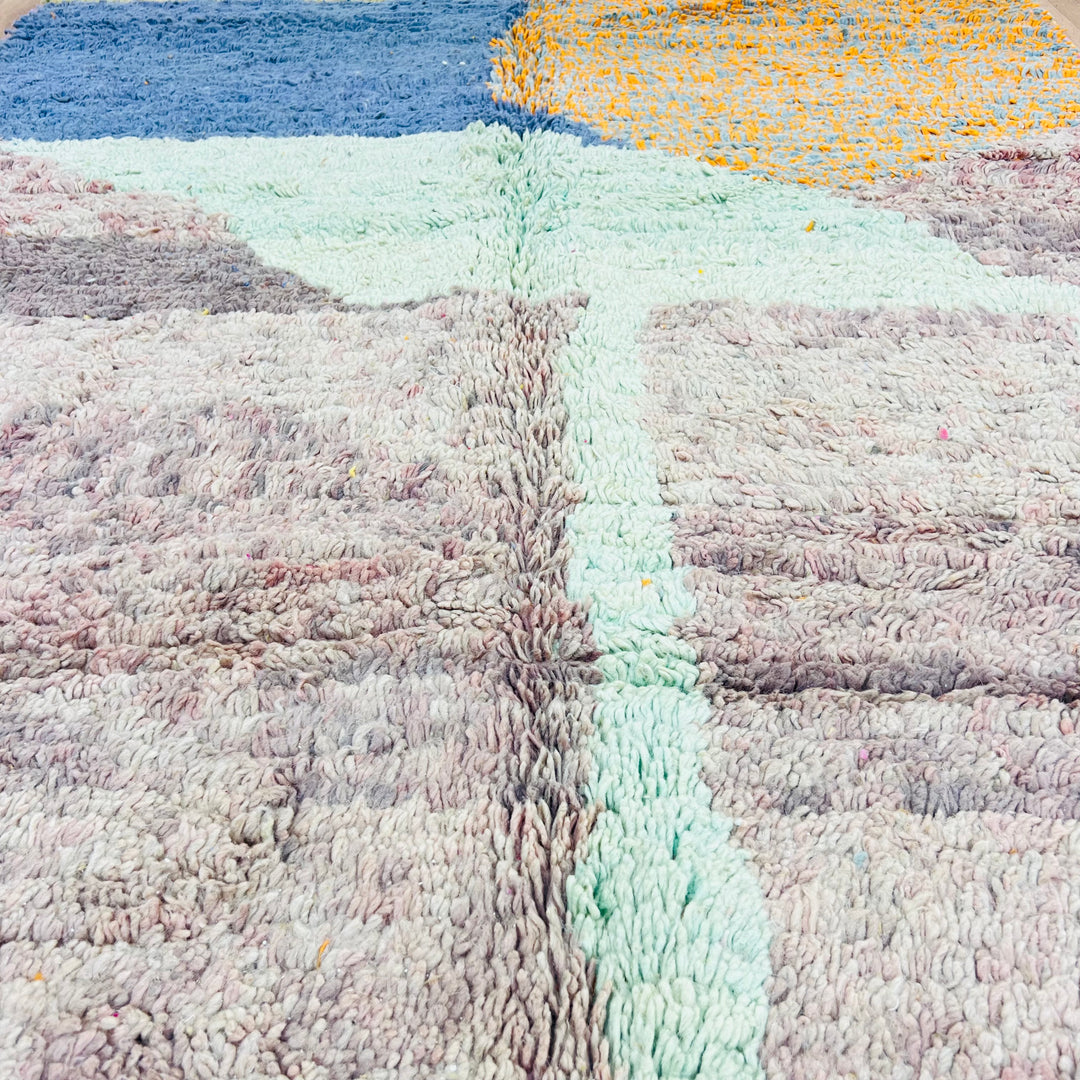 Abstract Moroccan wool rug with blue, green, and orange hues, showcasing traditional craftsmanship and a landscape-inspired design.