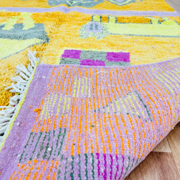 Bright Moroccan Berber rug with orange, pink, yellow, and grey geometric patterns, handcrafted with Amazigh motifs, showcasing vibrant artistry.