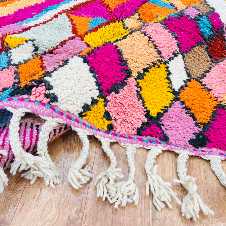 Colorful Moroccan Berber rug with vibrant diamond patterns in pink, orange, and turquoise, handwoven wool, perfect for a stylish area.