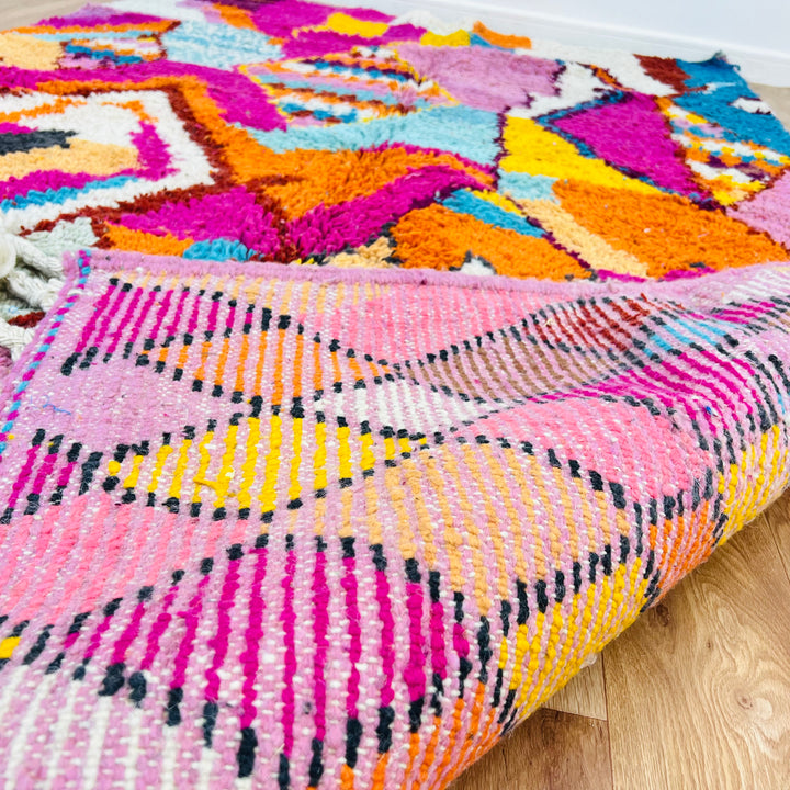 Colorful Moroccan Berber rug with vibrant pink, orange, turquoise shades, showcasing traditional motifs, handmade from wool.