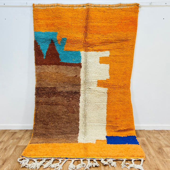 Colorful Moroccan wool rug with abstract motifs in orange, blue, and brown, handmade by Berber artisans. Size: 251 × 157 cm.