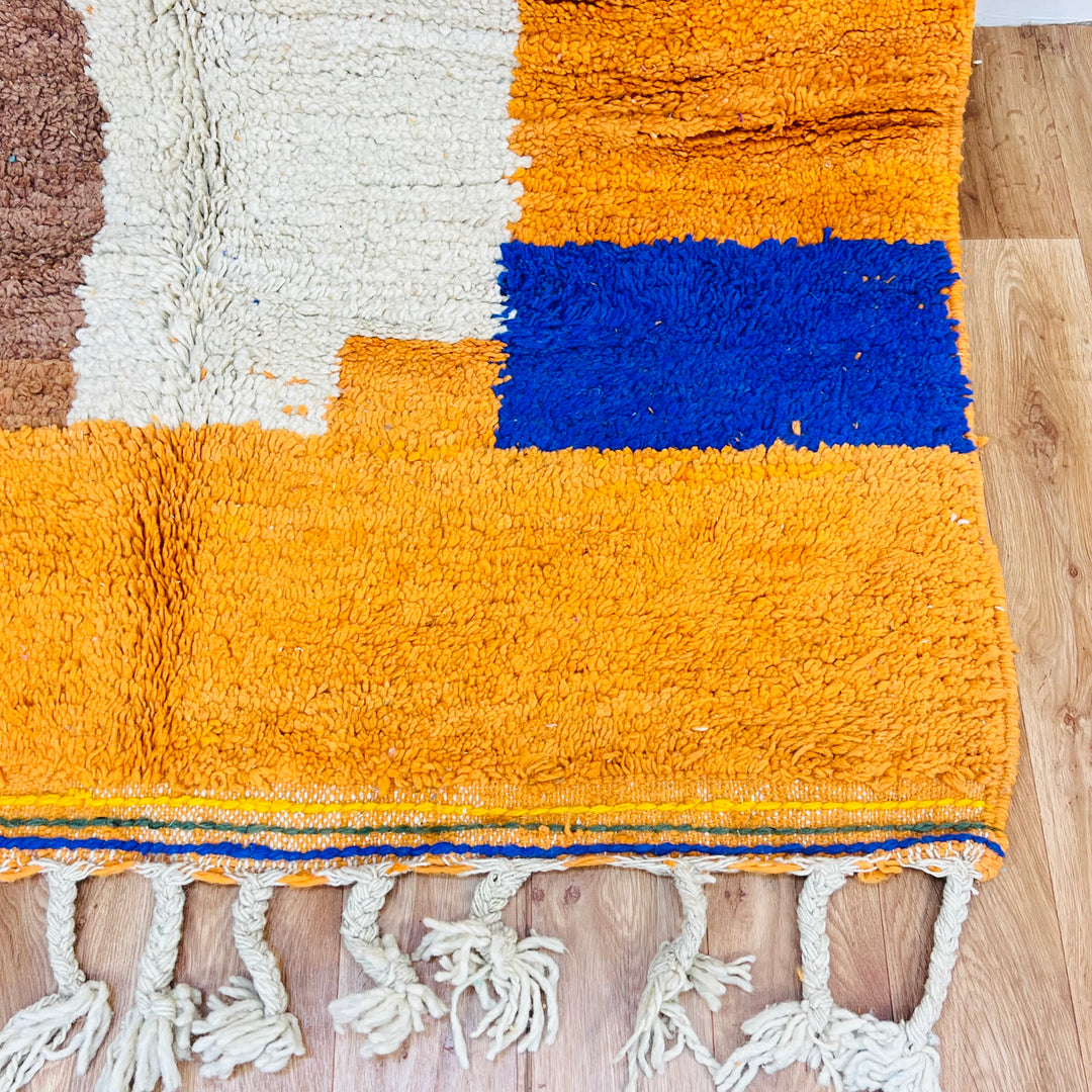 Vibrant Moroccan wool rug with colorful patterns, featuring orange and blue abstract designs, handmade by Berber artisans.